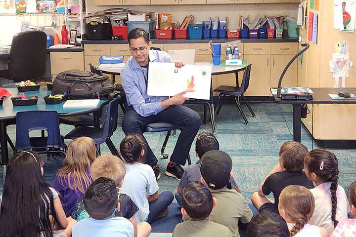 A man reads a picture book to a group of students
