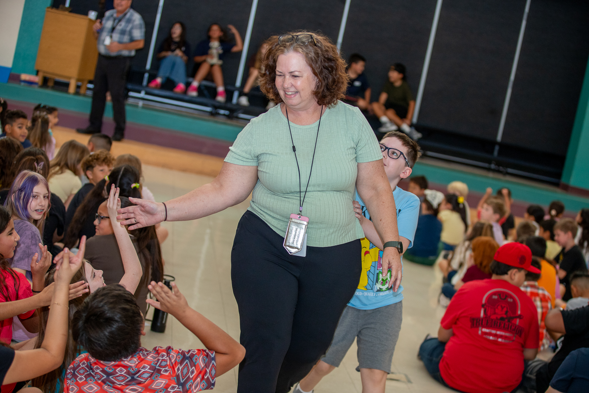 A woman gives students high fives as she walks through the cafeteria
